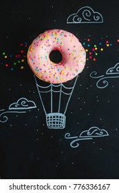 Pink Glazed Donut With Chalk Drawing Of Hot Air Balloon. Creative Concept. Low Key Food Photography.