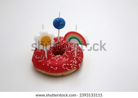 Pink glazed strawberry donut with springles and spring flower rainbow and earth day ecology space traveling on top snack and dessert foods served on white background