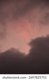 Pink and gray dramatic clouds at sunset in Gran Canaria, Canary Islands. Soft warm light breaking through dark sky creating an atmospheric, moody composition.
