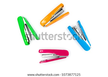 Pink and green and orange and blue stapler on a white background.