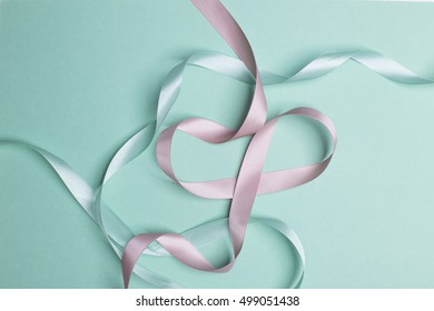 Pink And Green Satin Ribbon Swirls On Turqoise Paper