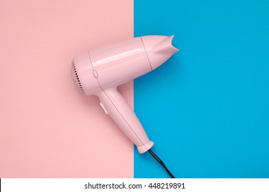 Pink hair dryer on pink and blue paper background