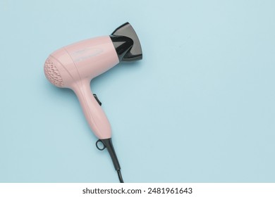 Pink Hair Dryer on Light Blue Background - Modern Haircare Appliance Stock Photo