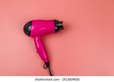 Pink hair dryer on a pastel pink background. Top view