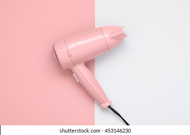 Pink hair dryer on pink and white paper background