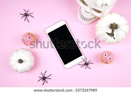 Pink Halloween smartphone evite ecard greeting card, party invitation mockup. Trick or treat party styled with white skull, pumpkins, black spiders, and spooky cupcakes. Negative copy space.