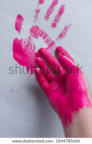 Pink handprint  and painted hand on grey paper