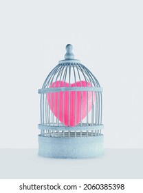 Pink heart captured in prison made of pastel blue cage. Minimal abstract creative concept of fallen in love. Romantic gift card or greeting card idea with pale gray background. Valentine day symbol. 