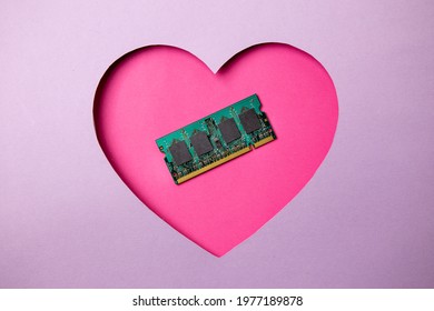 Pink heart shape on a purple background. At the heart are a memory frame for a computer and laptop. Minimal concept love computers.