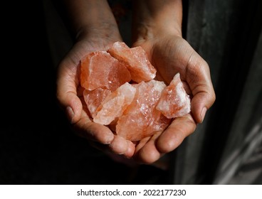 Pink himalayan salt pieces holding in hands. - Powered by Shutterstock