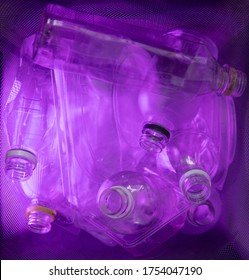 Pink Illuminated Recyclable Clear Water Bottles In Bin. Abstract Photo Depicting Future Of Global Recycle Effort And Mass Consumerism Plastic Waste Problem Solving.