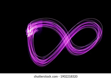Pink infinity sign on a black background. Long exposure photography.