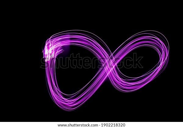 Pink infinity sign on a black background.\
Long exposure photography.
