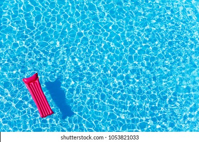 Pink inflatable mattress floating on water surface