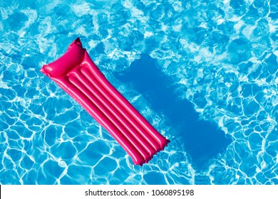 Pink Inflatable Mattress Floating On Water Surface