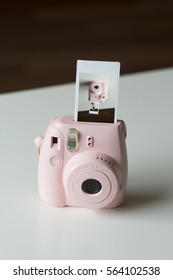 Pink Instant Camera With Film Coming Out Showing Shot Of Camera