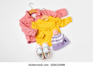 Pink Jacket And Jumper On Hanger  With Sneakers. Set Of Baby Clothes And Accessories For Spring Or Autumn  On  White Background. Fashion Kids Outfit. Flat Lay, Top View