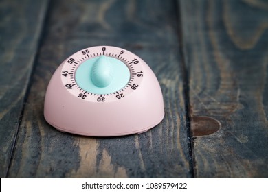 Pink kitchen cooking timer on blue wooden background