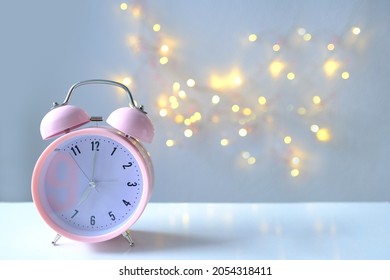 pink lady's alarm clock in retro style on light background with bokeh, 7 a.m., selective focus, copy space for designer, concept of routine of female life, device to get up on time, good morning