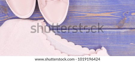 Pink leather shoes and sweater for woman lying on old purple boards