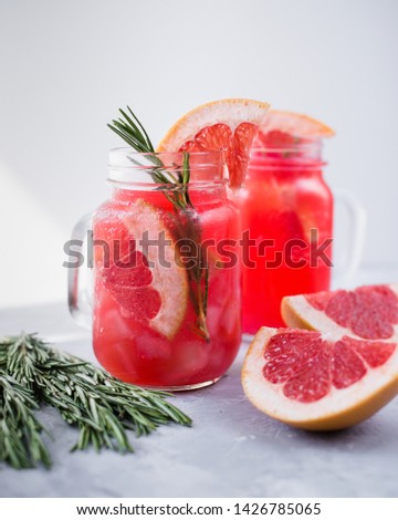 Pink lemonade with grapefruit, honey and rosemary in glass jar.