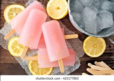 Pink Lemonade Popsicles With Ice Pail And Lemon Slices On A Rustic Wood Background