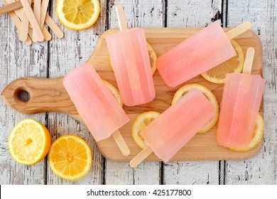 Pink Lemonade Popsicles With Lemon Slices On A Paddle Board With Rustic Wood Background