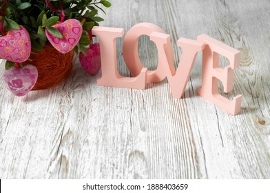 Pink letters and flowers on a wooden background. The word Love. Wooden volumetric letters. Valentine's Day. Wedding props.