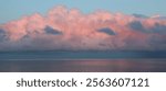 Pink lit cumulus cloud over Lake Vanern at sunset, Sweden.