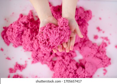 Pink magic sand in a kids hands on a white background close up. Early sensory education. Preparing for School. Development