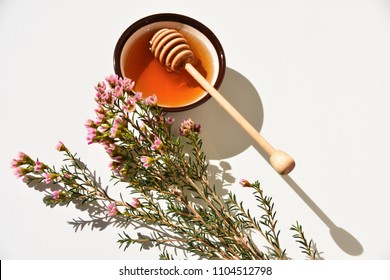 Pink manuka tree flower and manuka honey in a bowl, on a white background. Close up. - Shutterstock ID 1104512798