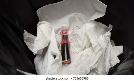 Pink Matte Lipstick Throw Away In Plastic Black Bag In Garbage With Tissue And Paper Background. Beauty Product Expiration Concept.