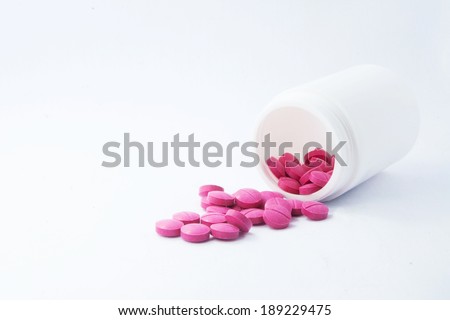 Pink medicine tablet antibiotic pills spilling out of a bottle