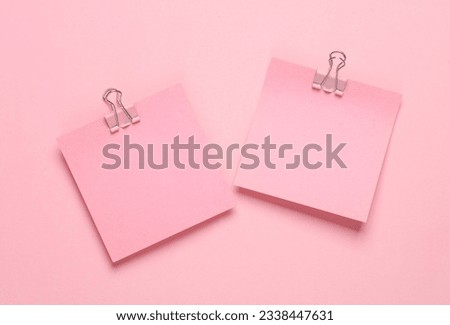 Pink memo papers with Paper clip holders on a pink background.
