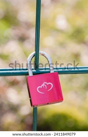 Pink metal lock on a fence in a park with an image of two hearts. Traditionally, people hang a padlock after a wedding to keep love in their hearts forever, Valentine's Day, High Quality Photo