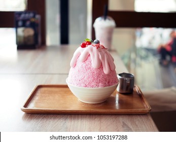Pink milk kakigori or Japanese shaved ice dessert flavored, Topped with pink whipped cream, blueberry and red currant, same as Bingsu Korean dessert.