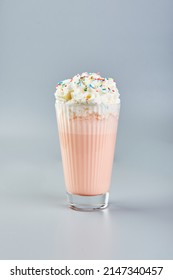 Pink Milkshake With Whipped Cream And Colored Sugar Sprinkles On Gray Background.