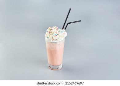 Pink Milkshake With Whipped Cream And Colored Sugar Sprinkles On Gray Background.