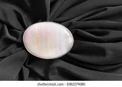 Pink Mineral Oval Brooch On Black Crumpled Silk Closeup