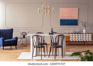 Pink and navy blue abstract painting on a gray wall with molding in an elegant dining and living room interior