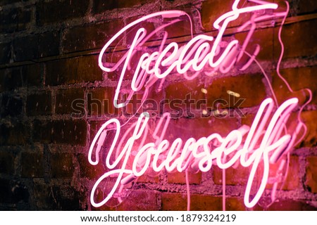 Pink Neon Treat Yourself sign on brick wall
