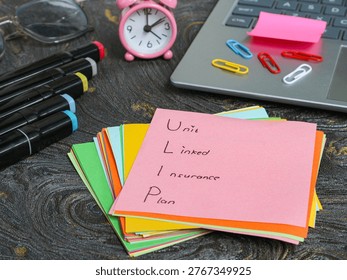 Pink note with Plan written on top of colorful sticky notes beside a laptop keyboard and paper clips in a workspace setting.