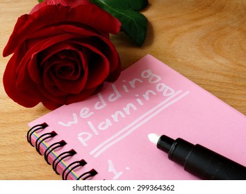 Pink notepad with wedding planning and rose.