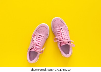 Pink nubuck sneakers isolated on a yellow background, seasonal shoes for walking and sports, top view