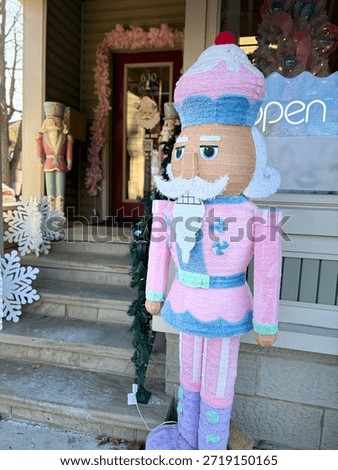 Pink nutcracker in front of a doll house
