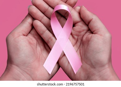 Pink October. Woman Holding Pink Ribbon On Pink Background.