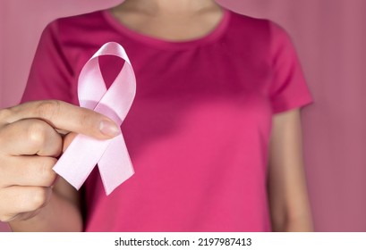 Pink October. Woman Holding Pink Ribbon On Pink Background.