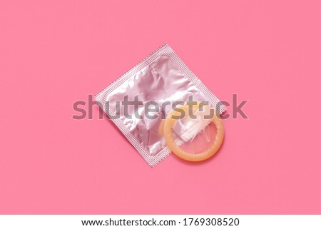 Pink opened condom and condom in pack on a pink background. A condom use to reduce the probability of pregnancy or sexually transmitted disease (STD). Safe sex and reproductive health concept.