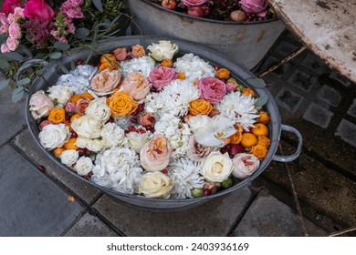 Pink and orange roses, blue hydrangea, red cranberries, white chrysanthemums, tangerines in water in a tin basin as a flower shop decoration - Powered by Shutterstock