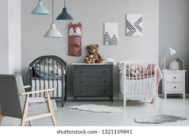 Pink Organizer On Wall Of Trendy Baby Bedroom With Two Cribs And Chest Of Drawers